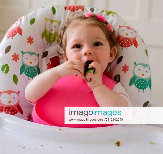 Baby led weaning girl eating grilled chicken meatballs for lunch