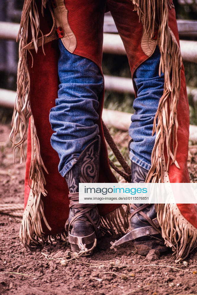 The fringed leather chaps and cowboy boots with spurs of a cowboy in the bull riding event in a