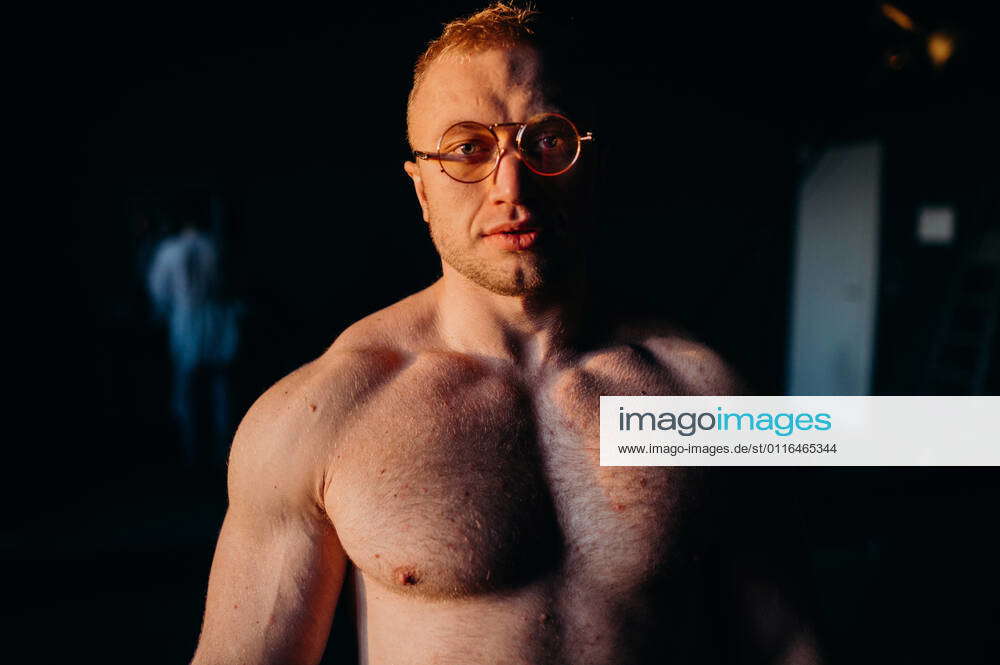 Muscular fitness shirtless man in glasses. Water drops on sport body