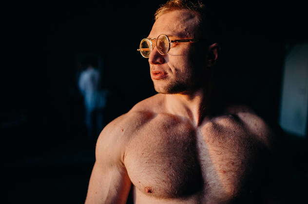 Muscular fitness shirtless man in glasses. Water drops on sport body