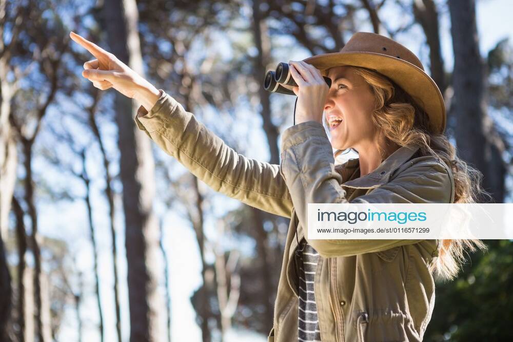 Woman using binoculars Woman using binoculars in the countryside, model