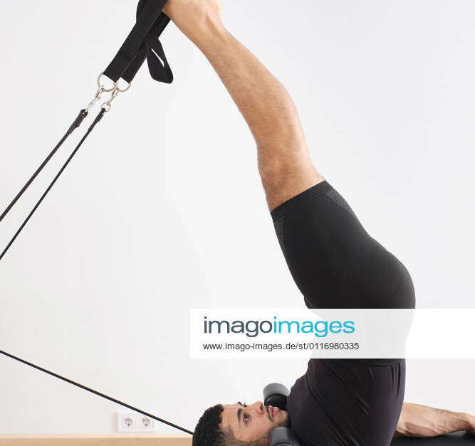 Male athlete with legs raised practicing pilates on cadillac