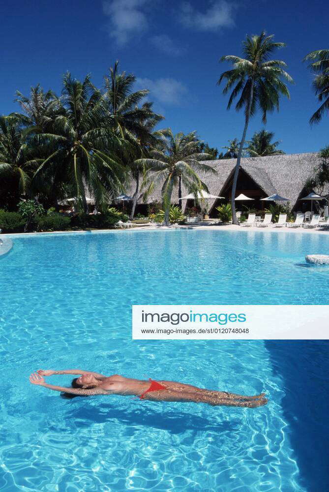 Woman topless in swimming pool of hotel complex, Manihi Island, Tahiti