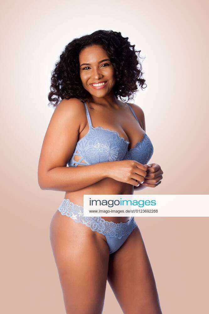 Beautiful happy plus size sexy woman with curly hair in light blue lingerie  bra and thong