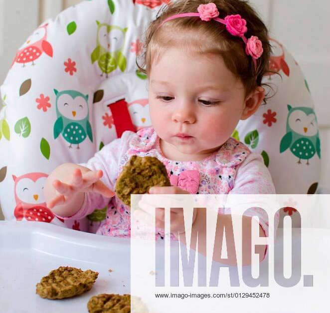 Baby led weaning girl eating grilled chicken meatballs for lunch