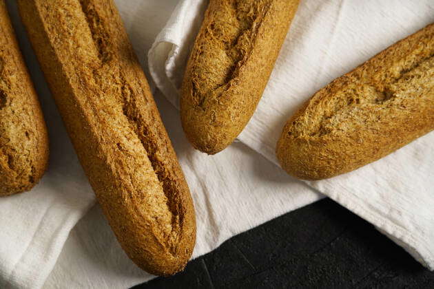 Loaf of fresh baked artisan whole grain baguette bread on raw linen ...