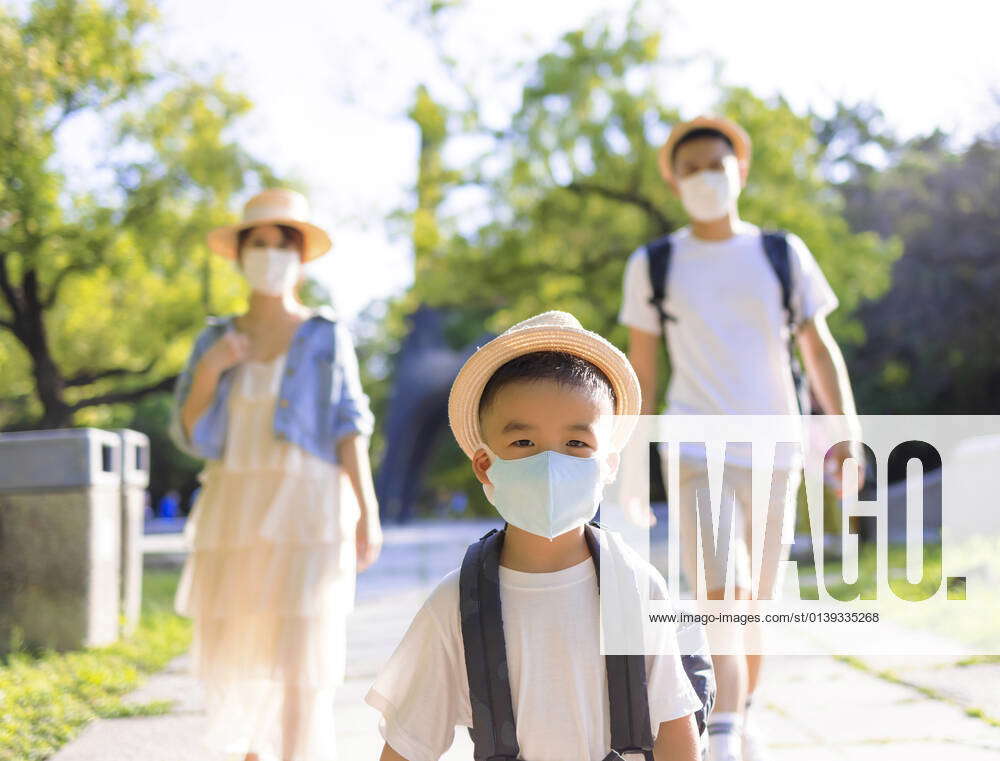 Happy family wearing the medical mask and walking in the park. Family