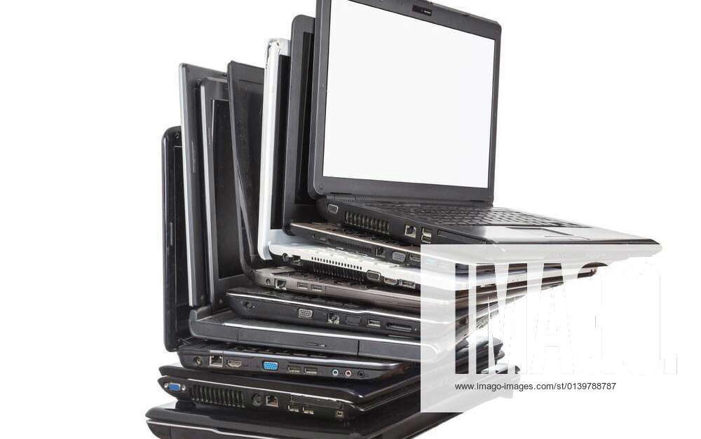 Stack of used laptops in different colors and models. T