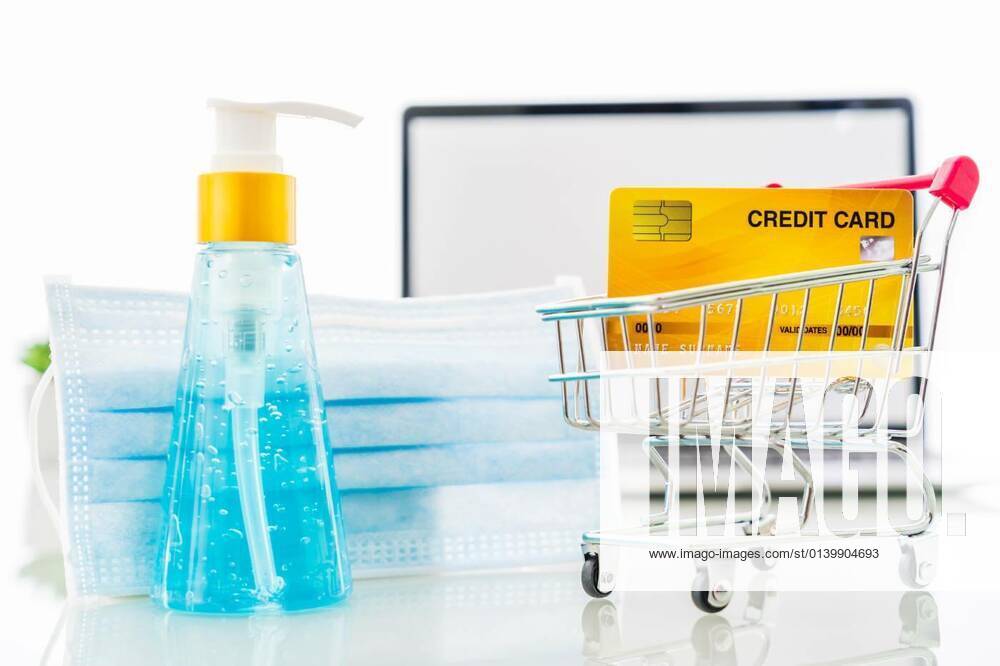 Credit card front of laptop screen with hand sanitizer and surgical mask