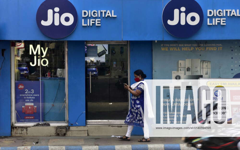 india-economy-a-woman-with-her-mobile-phone-walks-past-a-jio-store-in