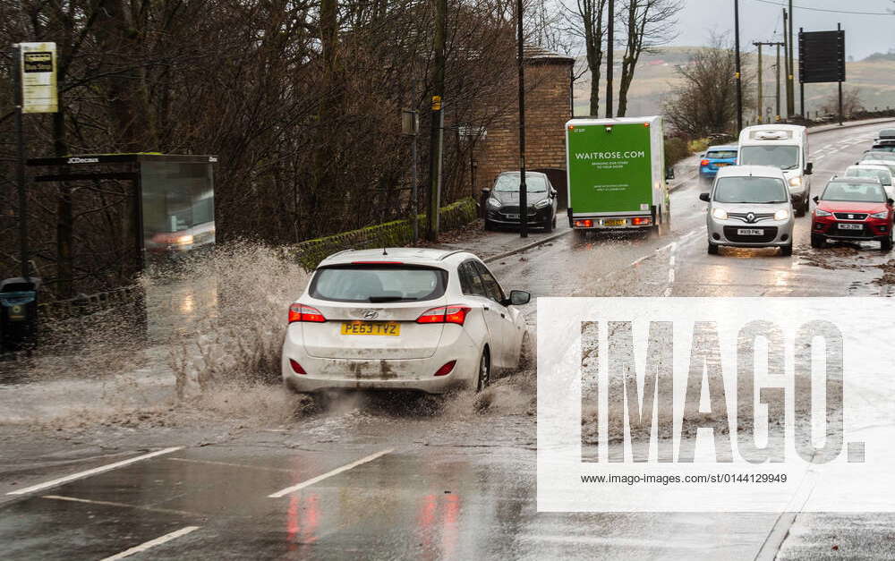 A car drives through flood water on the A62 Oldham Road in the village