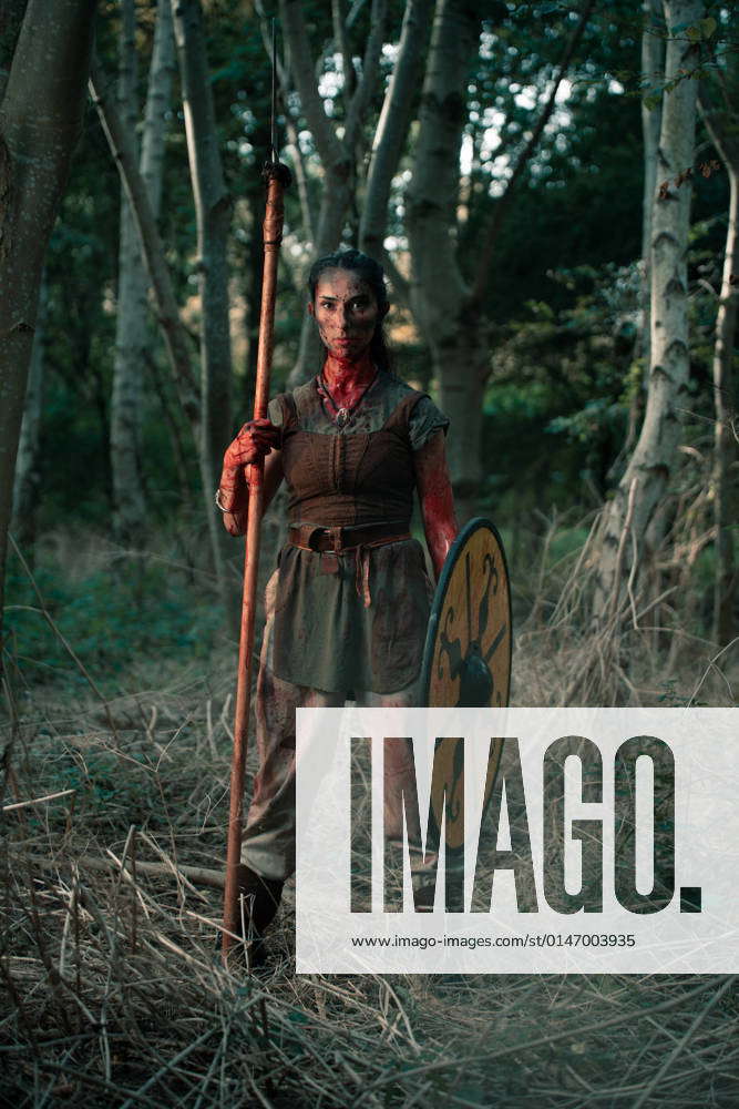 Full body of brave female in viking costume standing with spear and ...