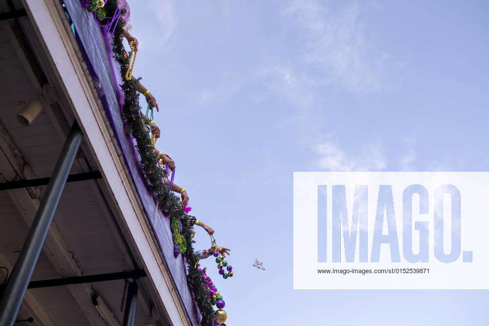 People on balconies throw beads to people celebrating Mardi Gras on