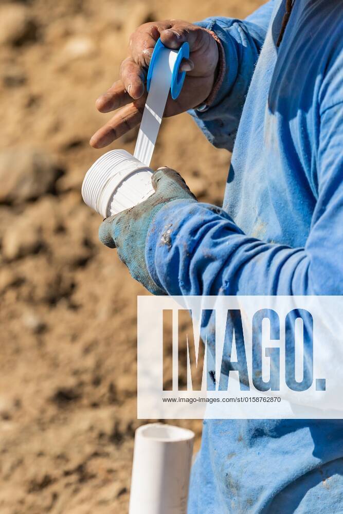 Plumber sticks PTFE tape on PVC pipe at construction site