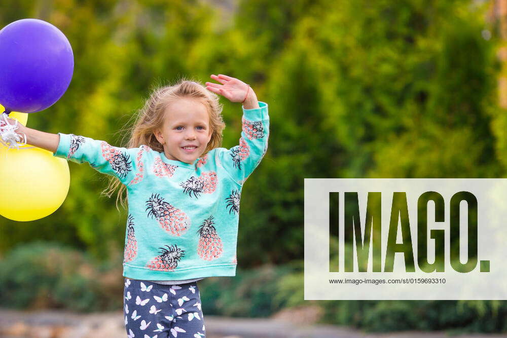 Happy cute little girl playing with balloons outdoors, model released ...