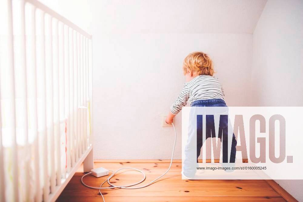 Little toddler playing with a plug. Domestic accident. Dangerous