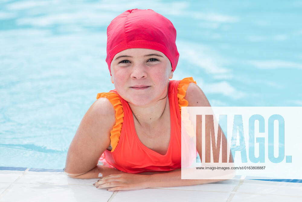 Concentrated cute little girl in swimsuit and rubber cap swimming in