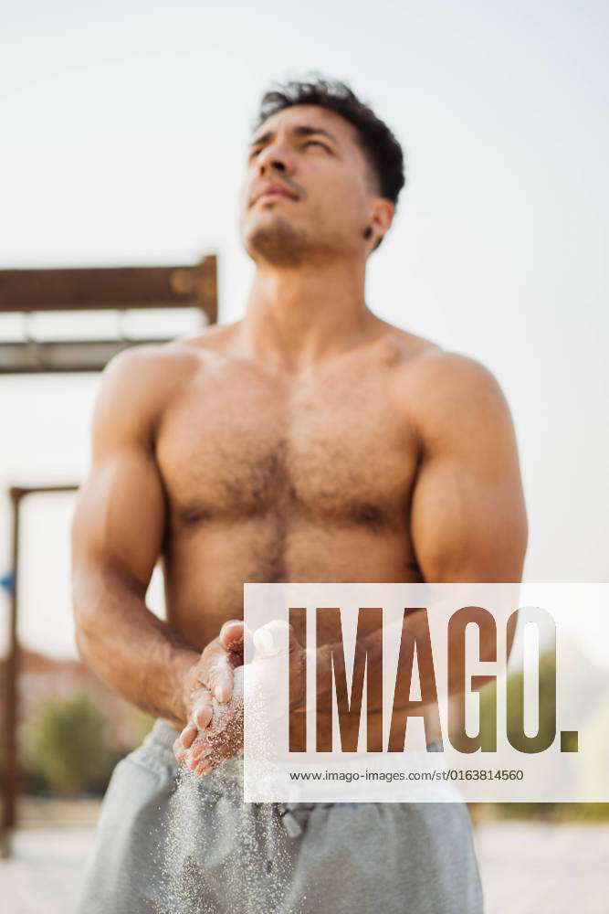 Muscular Hispanic Ethnic Male Athlete With Naked Torso Rubbing Sand On