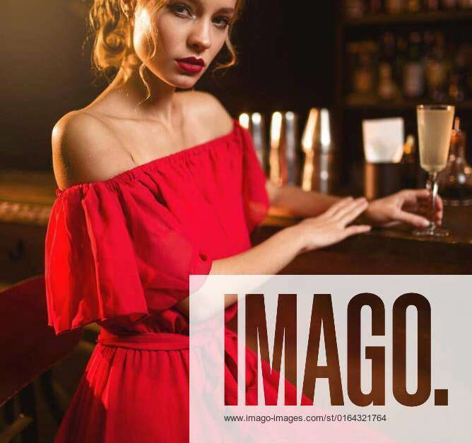 Woman in red dress standing at the bar counter, Portrait of young woman
