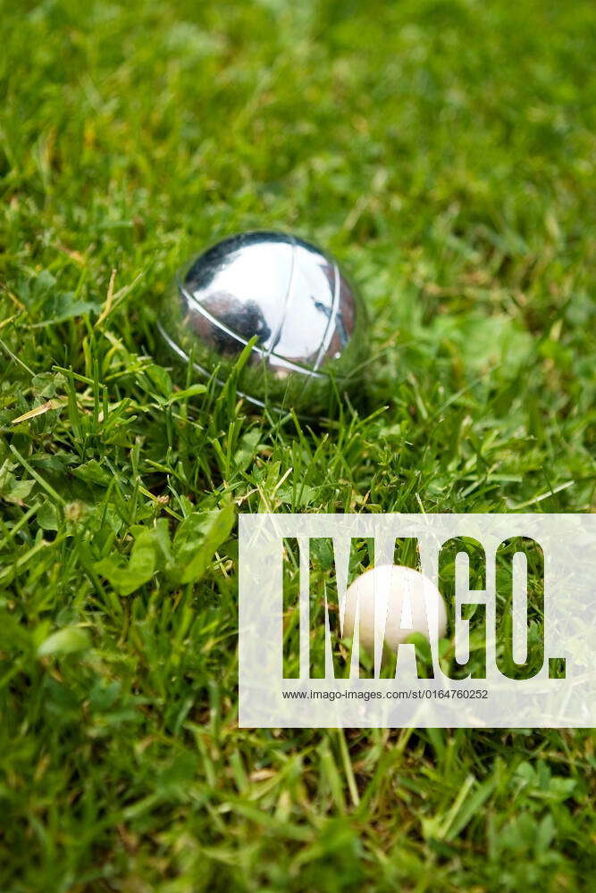Bocce balls sitting in the green grass, close to the target. shallow