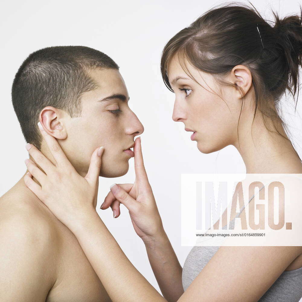 A young woman putting her finger over a young man s lips