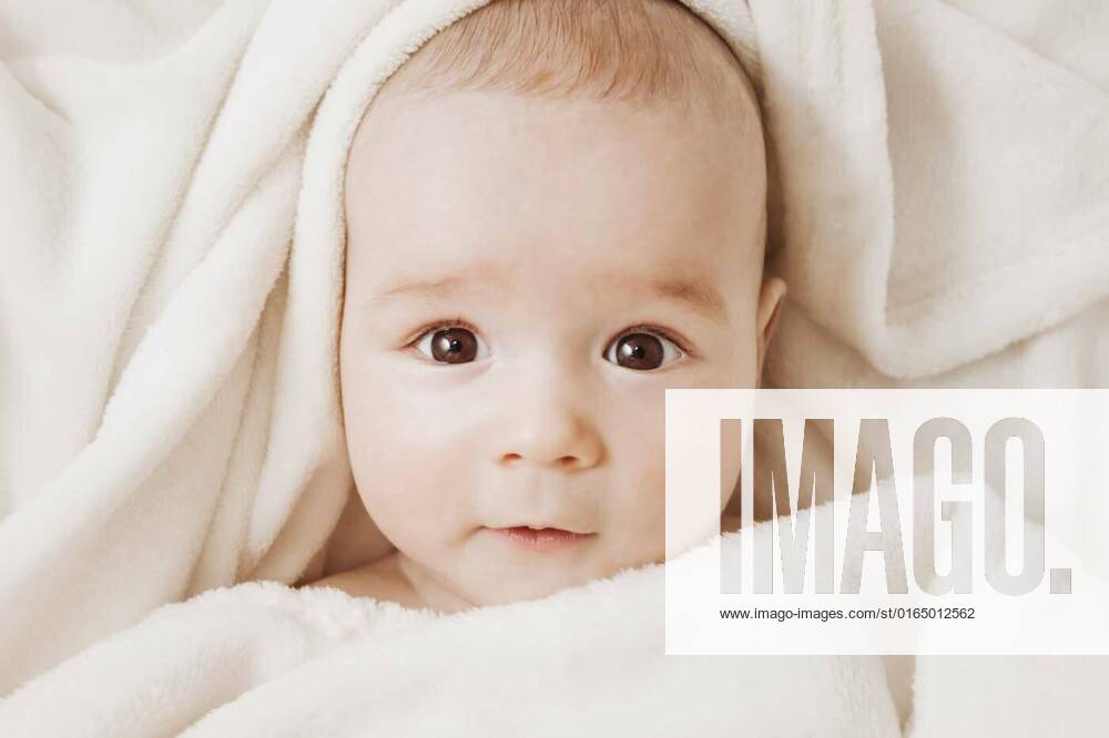 Cute baby lying in bed covered with soft blanket, little boy sleeping