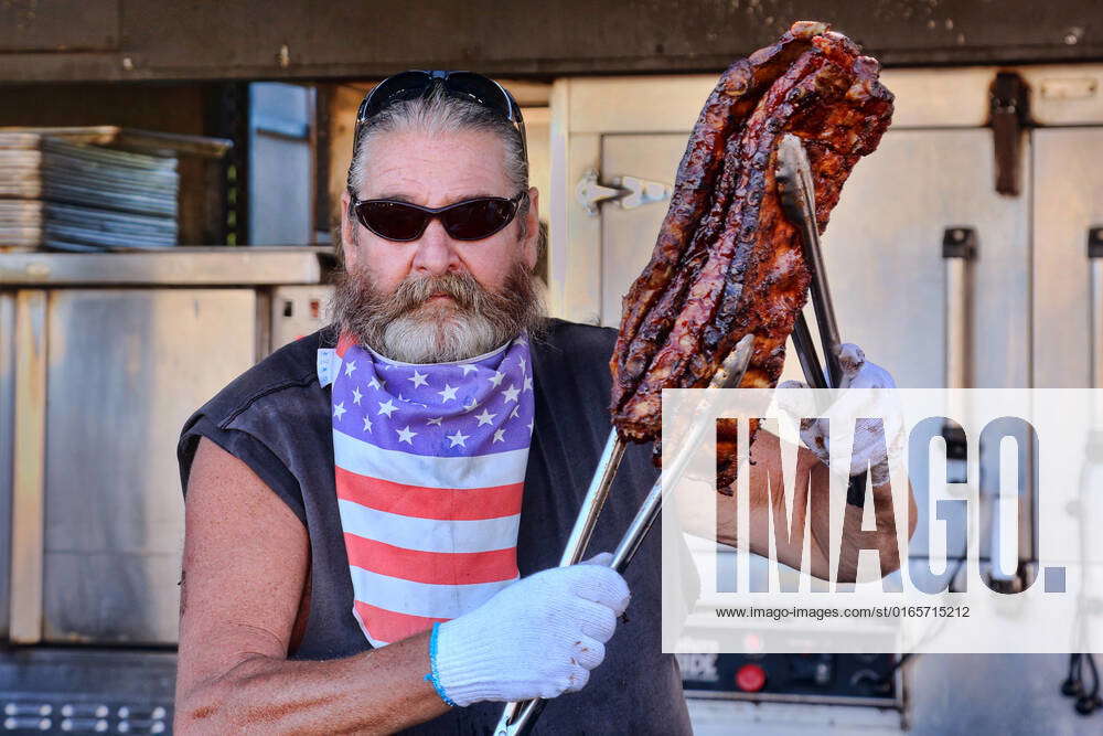 Northern Heat Rib And Beer Festival Barbecuer holds up racks of ribs