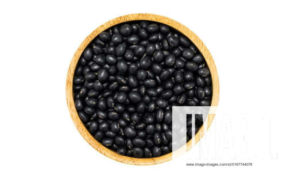Uncooked dry Black Soybeans in wooden bowl on white background, top