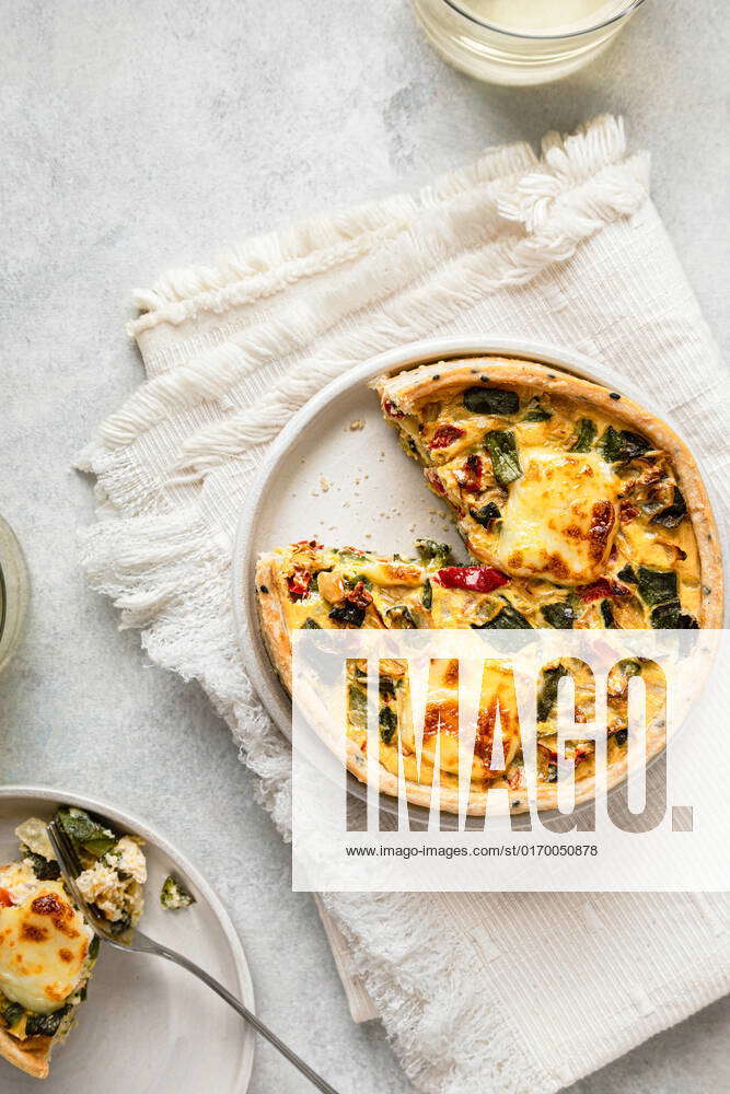 Studio shot of freshly baked zucchini quiche with red bell pepper and onion