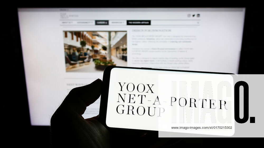 Person holding cellphone with logo of company YOOX Net-a-Porter Group S ...