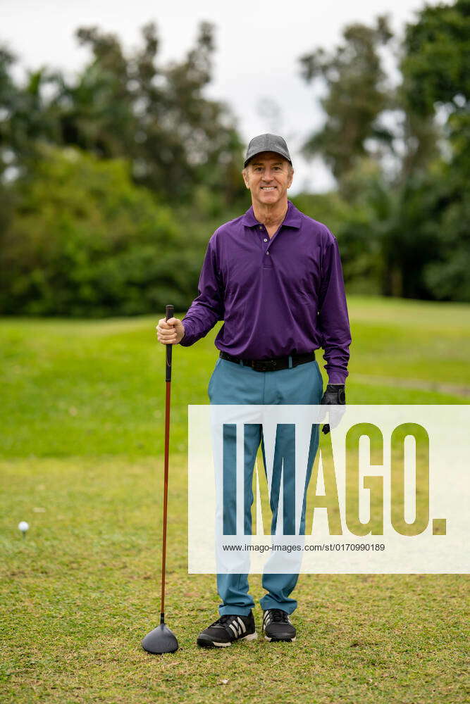 Handsome golf pro smiling at camera and holding club Handsome golf pro ...