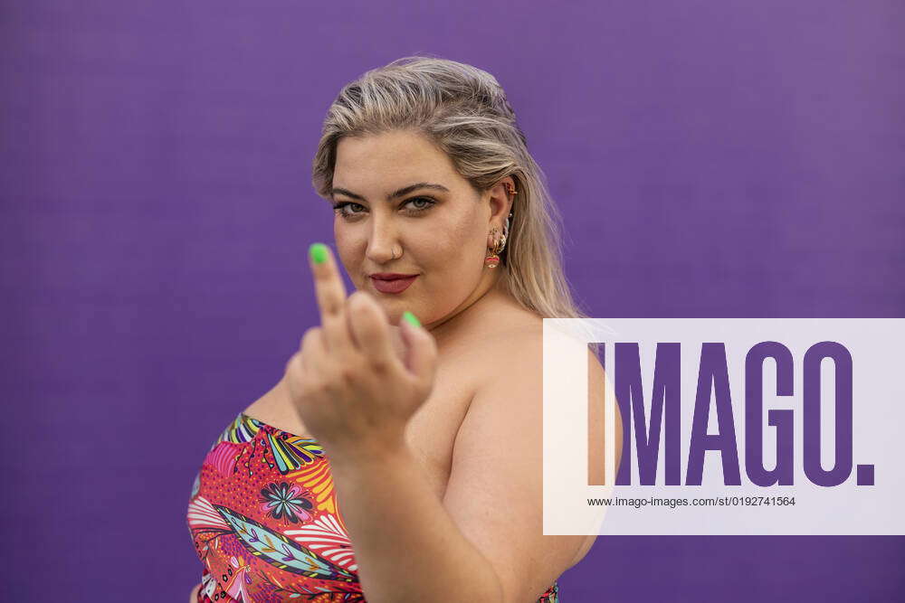 Obcene Images Young woman doing obscene gesture in front of purple wall model ...