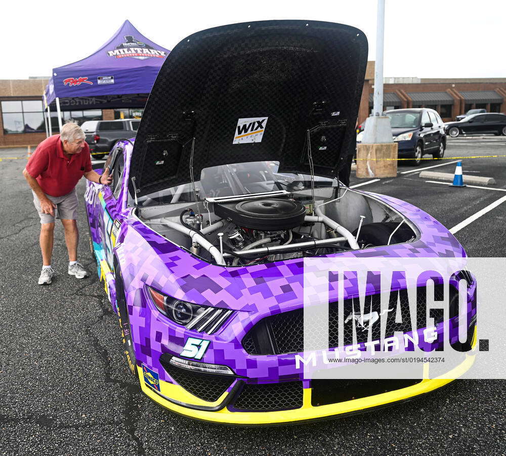 A NASCAR fan admires a Rick Ware Racing Team race car parked outside ...