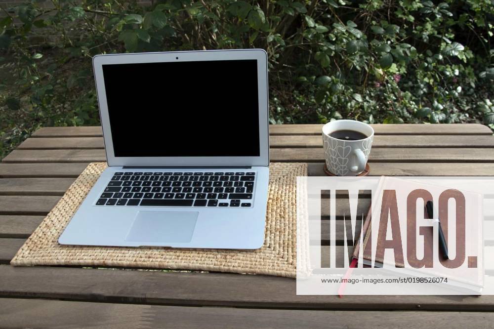 Home working in garden with laptop, Working from home with laptop, coffee and notebook in garden