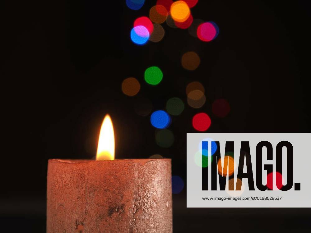 First Advent candle burns with Christmas lights bokeh, First Advent