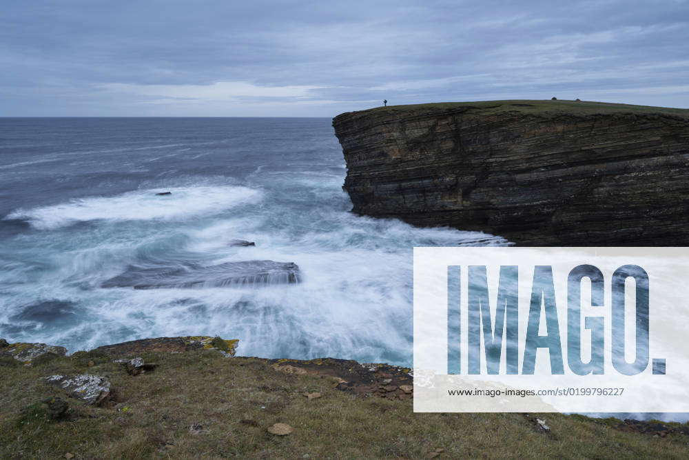 Photographer on cliffs above wild sea at Yesnaby, Orkney, Scotland ...