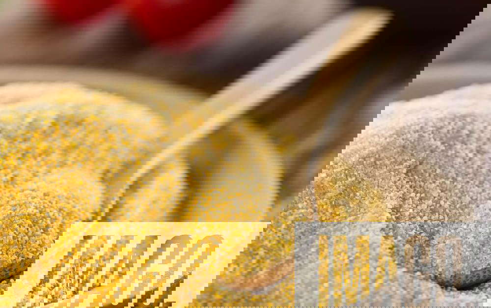 Raw coarsely ground cornmeal or polenta, Raw coarsely ground cornmeal or polenta on wooden plate