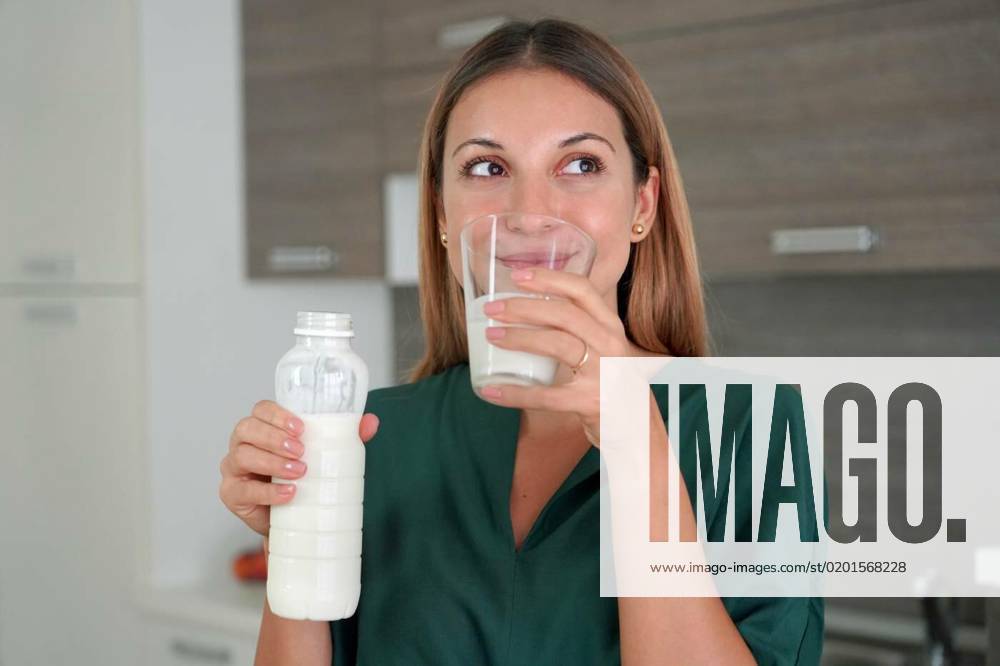 Portrait of young smiling woman drinking kefir. Beautiful girl holds a ...