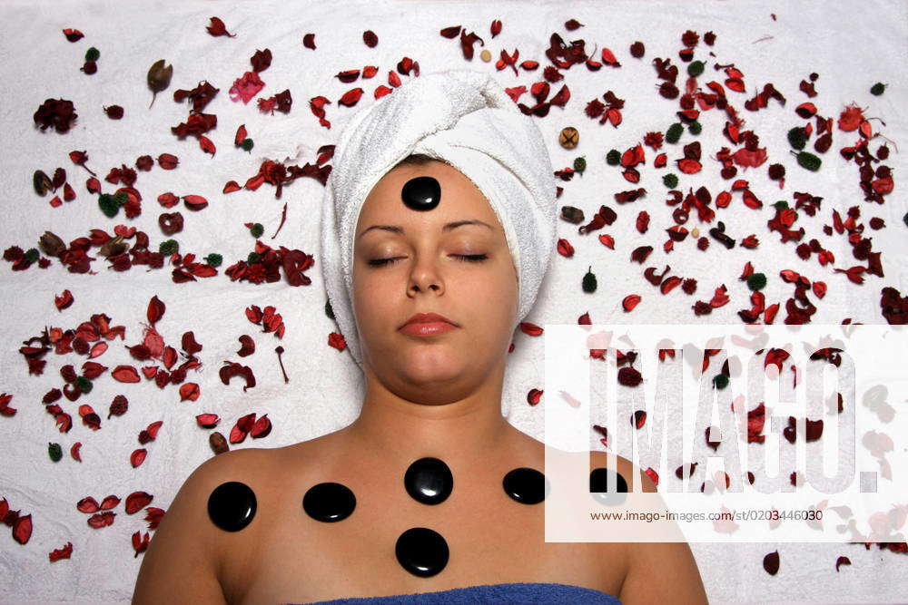 Spa Treatment Woman Relaxed Itself At A Hot Stone Massage Surrounded From Red Bluetenblaettern 