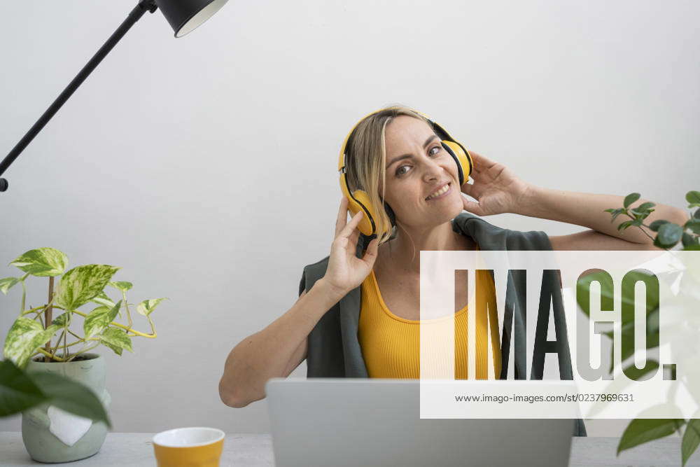 Happy freelancer wearing wireless headphones sitting at desk model ...