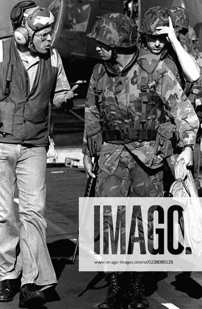 A flight deck crewman talks to a Marine who is preparing to board a ...