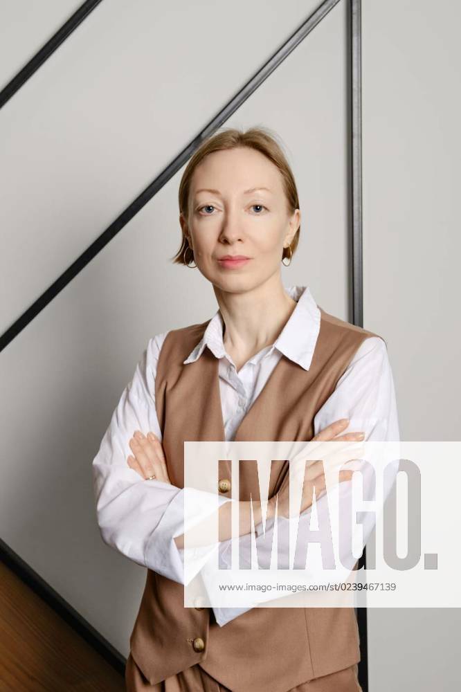 Young adult woman dressed for success, A young adult woman stands indoors with crossed arms, wearing