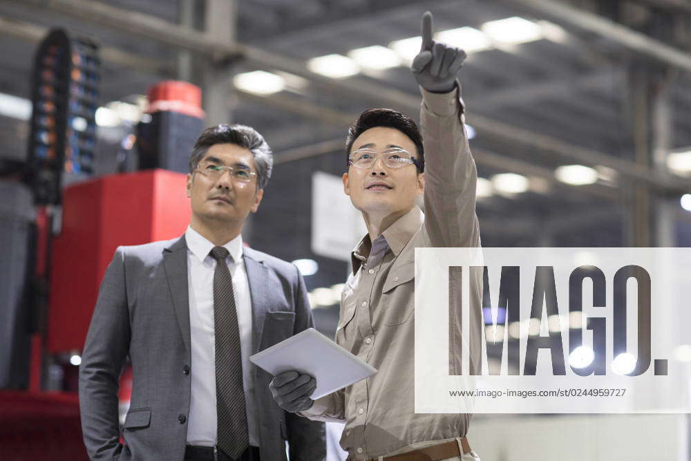 Chinese businessman and engineer talking in the factory Beijing China