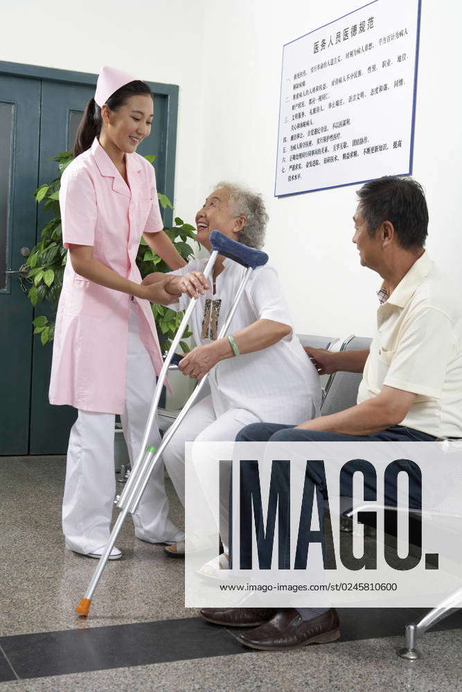 Chinese Nurse Helping Woman Stand Up With Crutches Beijing China