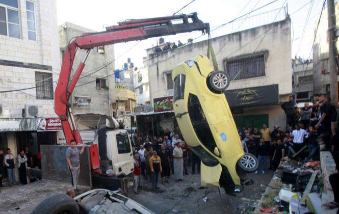 Palestinians inspect the damage during a military raid in the West Bank ...