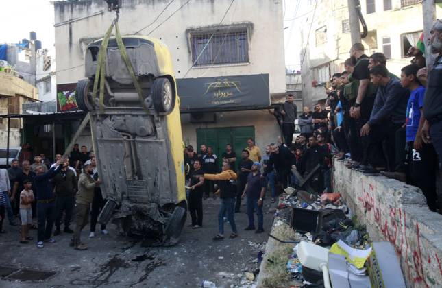 Palestinians inspect the damage during a military raid in the West Bank ...