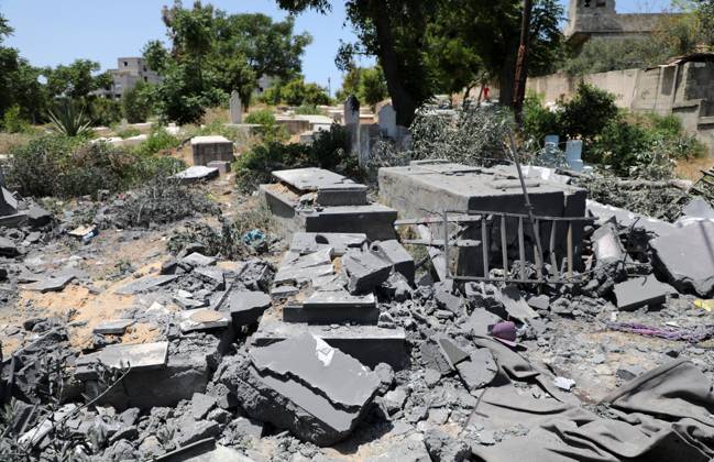 Palestinians inspect the rubble of a cemetery following an Israeli air ...