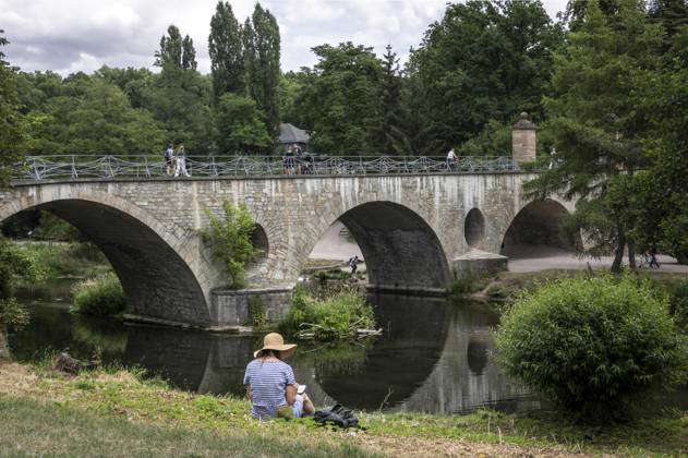 Weimar Relaxing on the Ilm River A young woman in a straw hat sits on ...