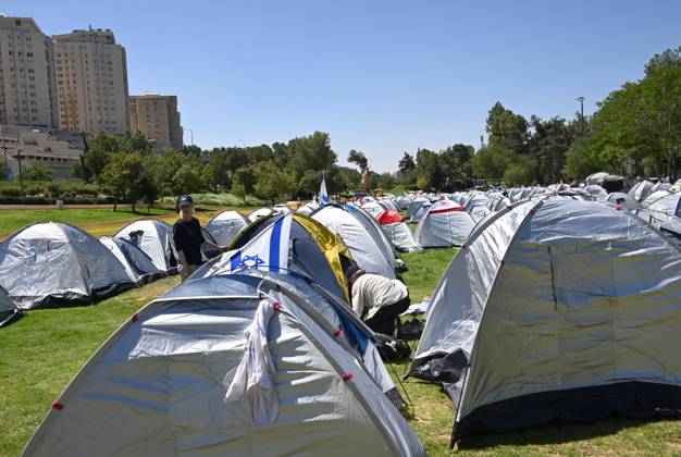 Israelis secure their tent in an encampment set up by anti-government ...