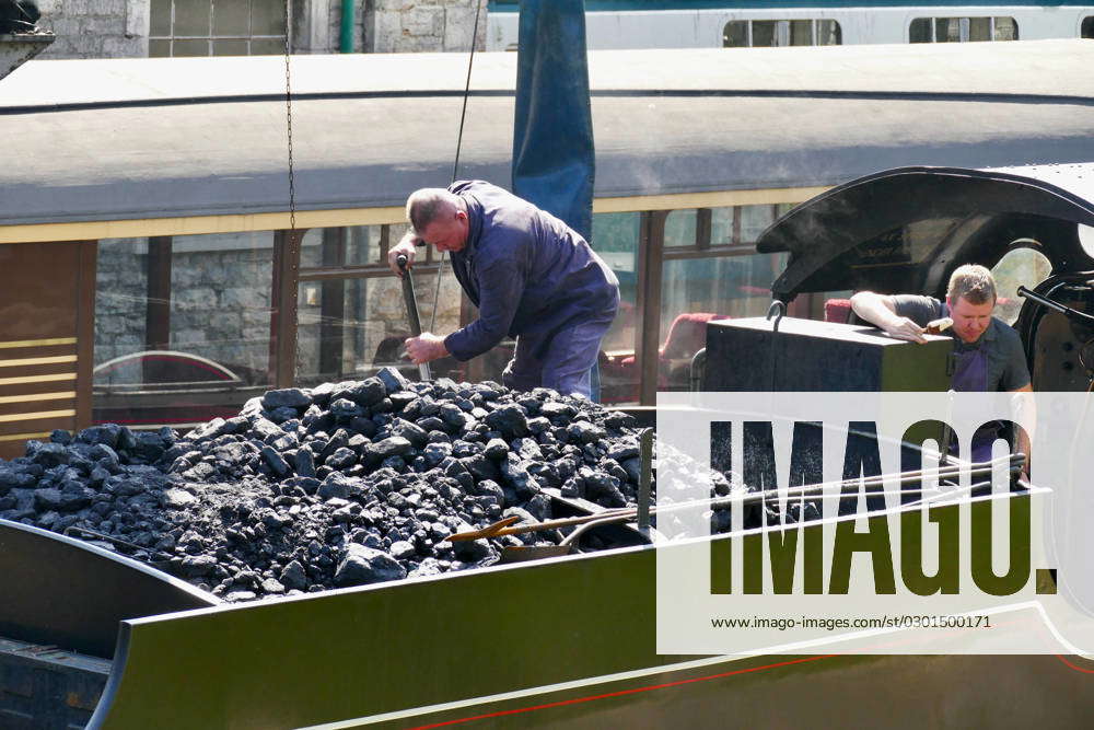 Seasonal weather Steam train drivers shovel coal in the heat whilst ...